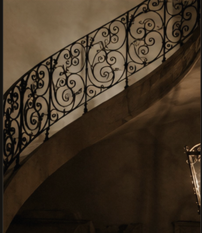 Ornate wrought-iron railing along a curved staircase.