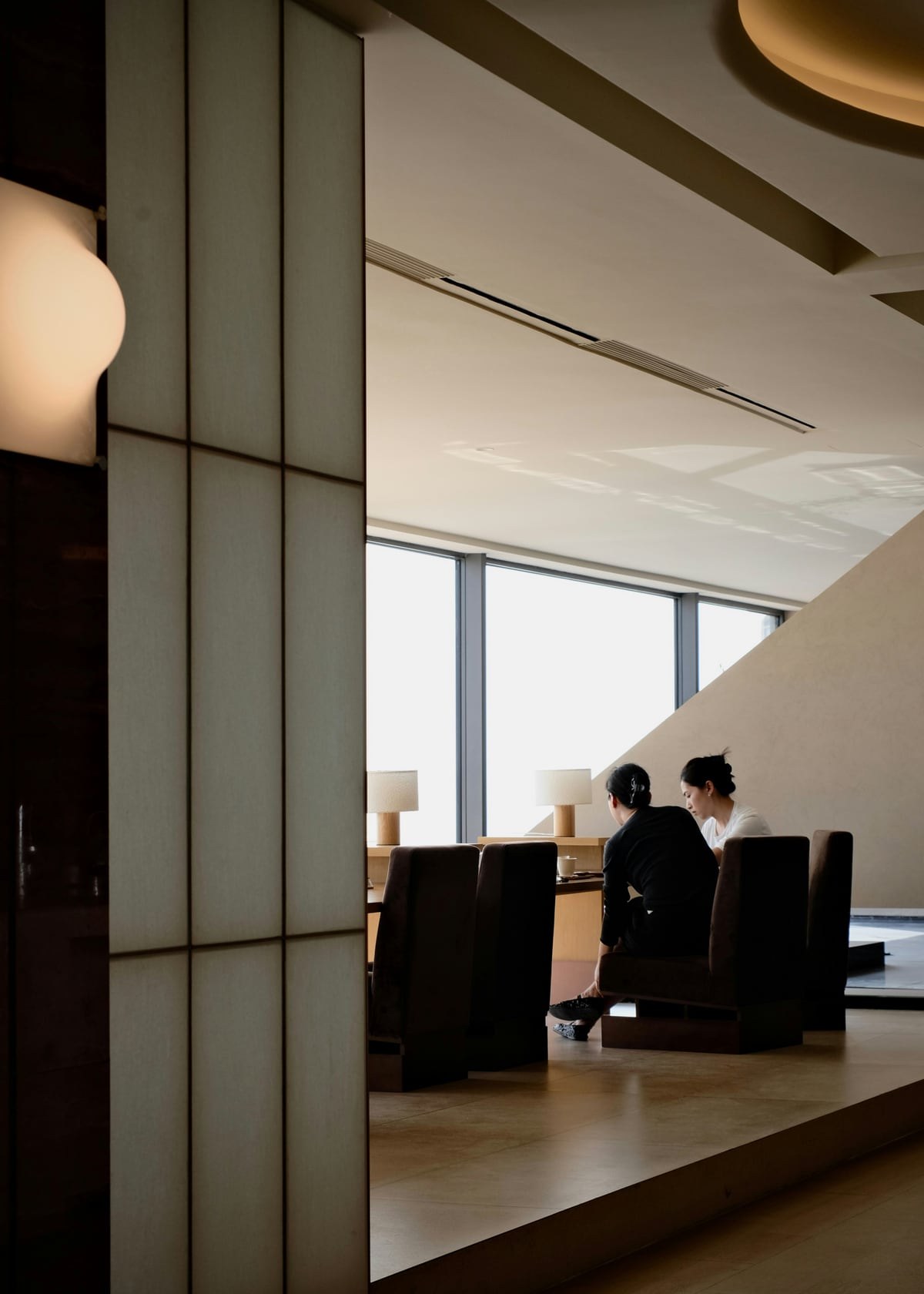 Guests conversing beside tall windows in an elegant interior.